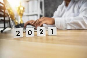 Número cúbico de 2021 en mesa de madera con hombre de negocios foto