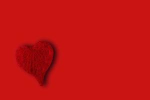 red heart in the lower left corner on a red background. Concept of St. Valentine's Day photo