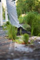 Person in blue denim jeans and black shoes standing on concrete pathway photo