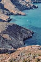 White boat on sea near brown rock formation during daytime photo