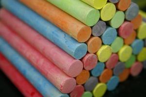 Set of colorful pieces of chalk on blackboard photo