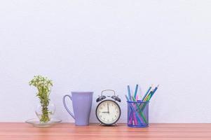 Pencils, pens and clock on the desk photo