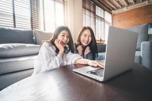 Two women using laptop at home photo