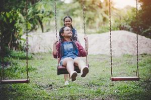 Two young girls sitting on a swing together photo