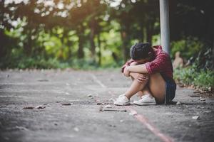 niña triste sentada en un parque foto