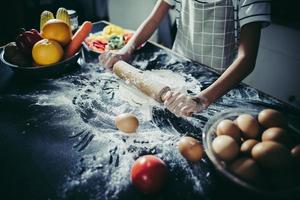 Little chef using rolling pin to stretch the dough photo