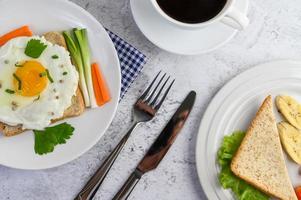 A fried egg on toast topped with pepper seeds with carrots and spring onions photo