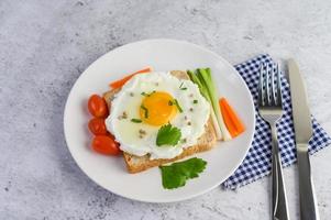 A fried egg on toast topped with pepper seeds with carrots and spring onions photo