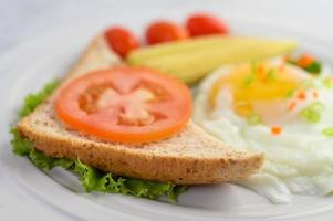 A fried egg with toast, carrots, baby corn and spring onions photo