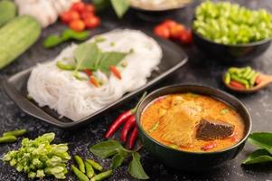Chicken curry in a black cup with rice noodles photo