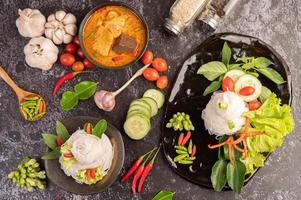 Chicken curry in a black cup with rice noodles photo