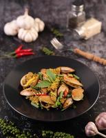 Clams fried with curry powder on a black plate photo