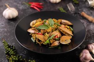 Clams fried with curry powder on a black plate photo