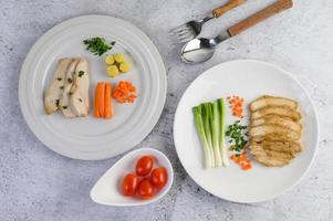 Steamed chicken breast on a white plate with spring onions and carrots photo