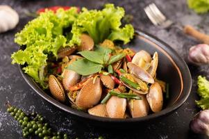 Clams fried with curry powder on a black plate photo