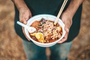 persona de pie con fideos en una taza de espuma foto