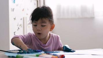 menina asiática pintando com as mãos no papel video