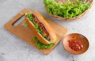 Hotdog with lettuce and tomato on a wood cutting board photo