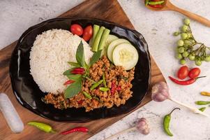 Spicy minced pork salad with rice, chili's, and tomatoes on a black plate photo