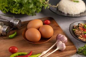 Three chicken eggs with garlic, tomatoes and chili photo