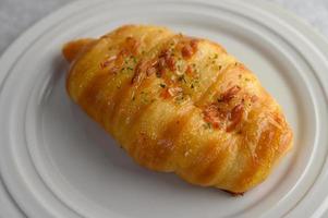 A sausage bread roll with hotdog on white plate photo