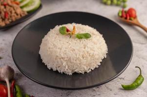 Spicy minced pork salad with rice, chili's, and tomatoes on a black plate photo