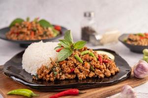 Spicy minced pork salad with rice, chili's, and tomatoes on a black plate photo