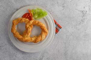 Freshly baked soft pretzel on a white dish photo