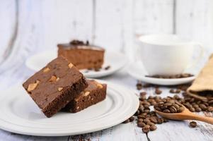 Chocolate brownies on a white plate and coffee beans on a wooden spoon photo