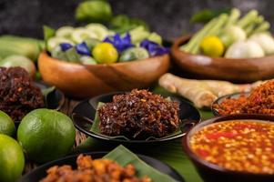 Chili paste served on banana leaves surrounded by long beans, lime, chili and eggplant photo