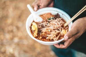 persona de pie con fideos en una taza de espuma foto