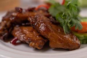 Chili paste fried chicken wings on a white platter with chili and coriander photo