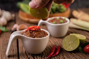 Red eye chili paste with lemon and chili on wooden board photo