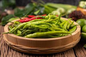 Fresh chili on a wooden tray with lemon and kaffir lime photo