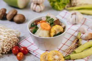 Chicken soup with corn, shiitake mushroom, enoki mushroom and carrot photo