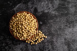 Frijoles amarillos en un cuenco de madera sobre fondo negro foto