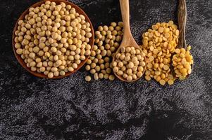 Frijoles amarillos en un cuenco de madera sobre fondo negro foto