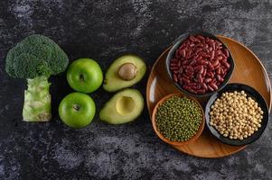 Broccoli, apple and avocado with beans on a black cement floor background photo