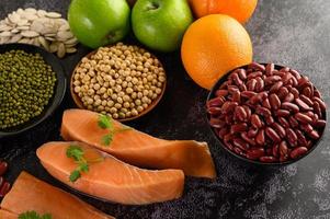 Legumes, fruit, and salmon on a black cement background