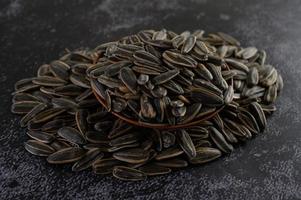 Sunflower seeds in a wooden bowl on black surface photo