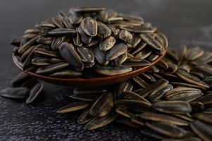 Sunflower seeds in a wooden bowl on black surface photo