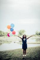 Mujer joven sosteniendo globos de colores en la naturaleza foto