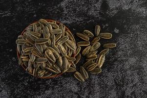 Sunflower seeds in a wooden bowl on black surface photo