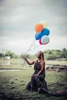 Young woman holding colorful balloons in nature photo