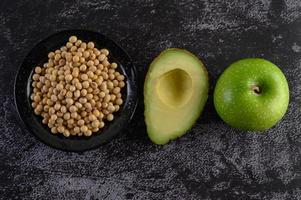 Avocado, apple and soybeans on black cement background photo