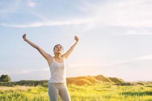 Happy beautiful woman with stretched arms in a meadow photo