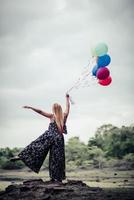 Mujer joven sosteniendo globos de colores en la naturaleza foto