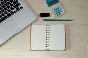 Desk with notebook, pencil, calculator, and computer photo