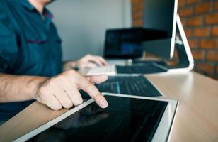 Software developer pointing at tablet photo