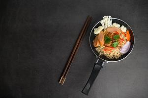 Bodegón con fideos en una sartén y palillos. foto